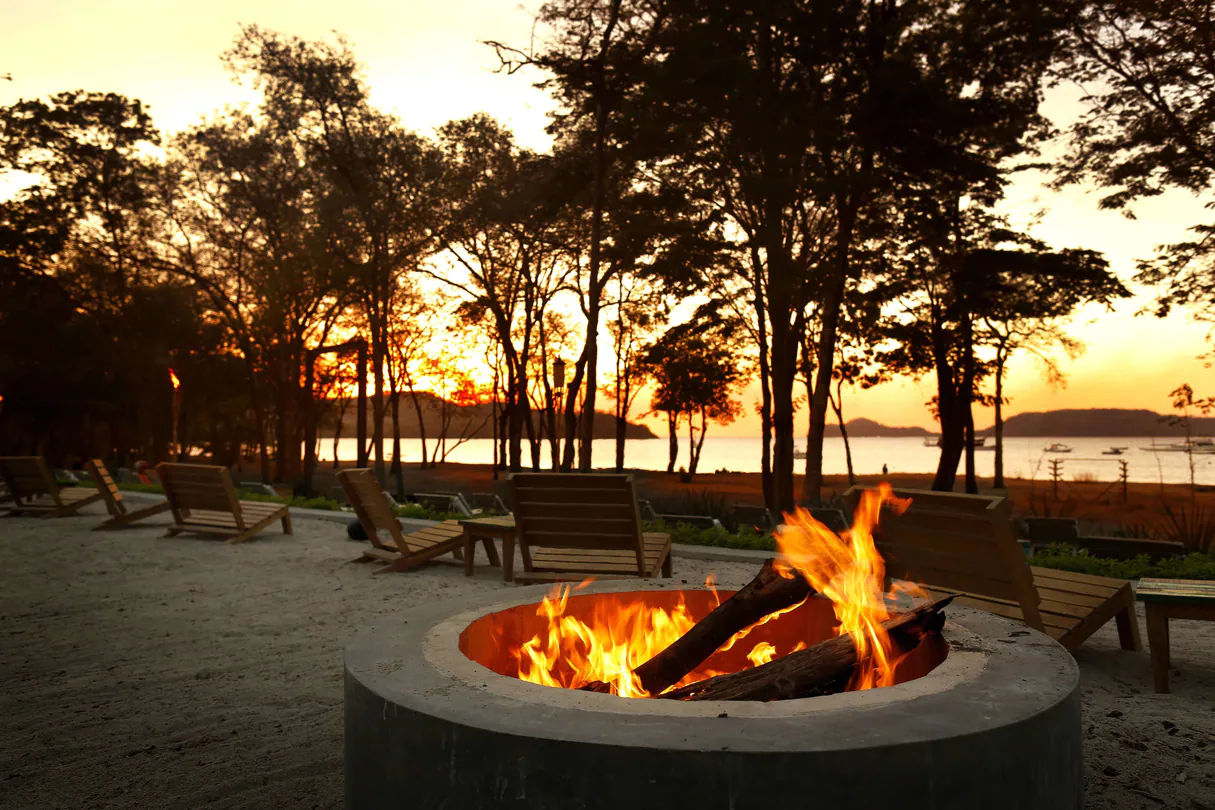 Photo of the El Mangroove hotel & resort grounds.  Beautiful sunset through the trees, with a lit firepit in the foreground.